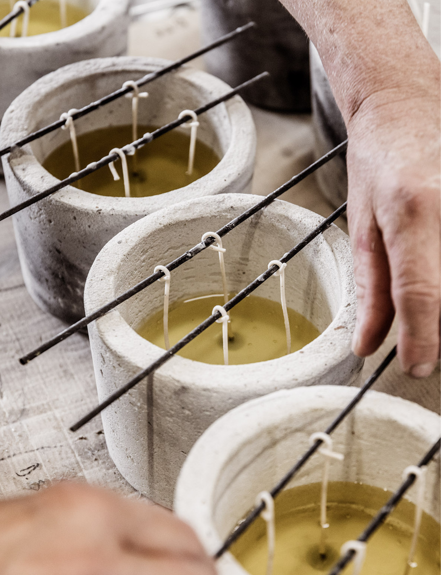 Candles that had just been filled with a bit natural wax. The craftsman is making sure the wicks are positioned straight.