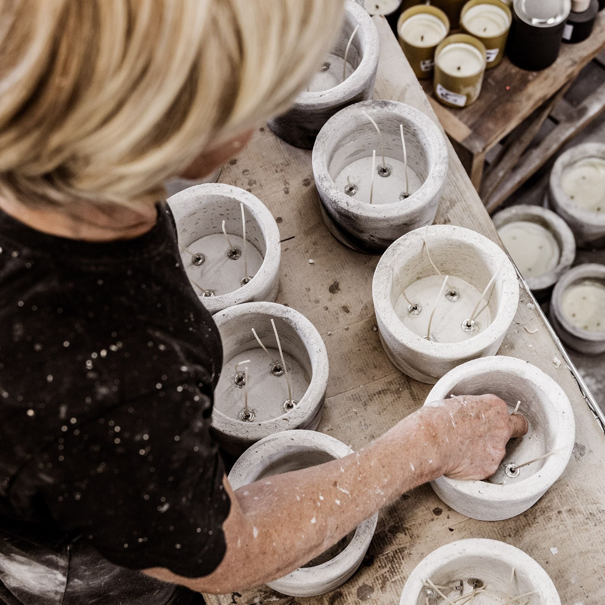 The manufacturing process of Mon Dada candles. Mom boss placing wicks in concrete candle pots that will become Mon Dada candles.