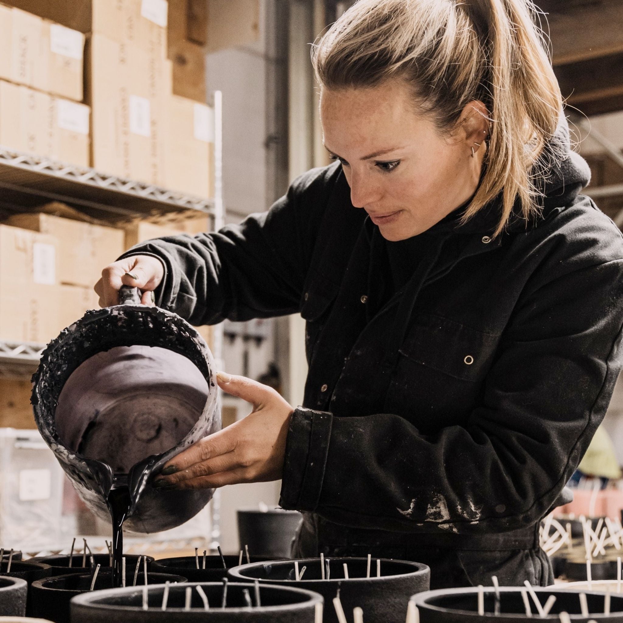 Candle boss pouring natural candle wax in pots.