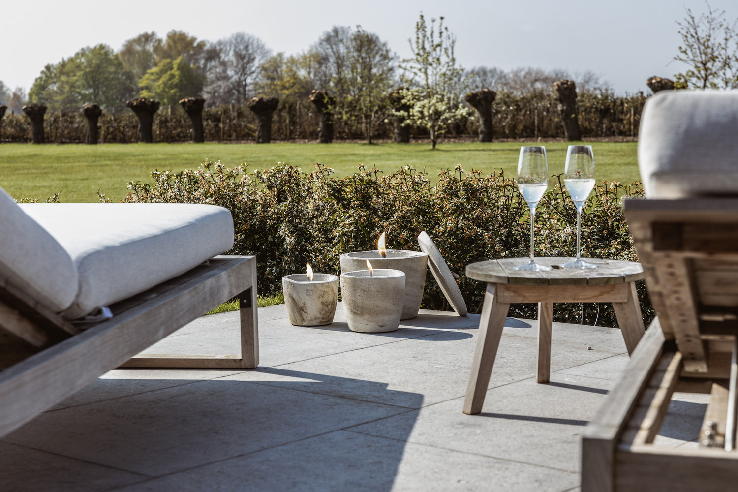 Patio with outdoor candle set and glasses of champaign with a view on the garden