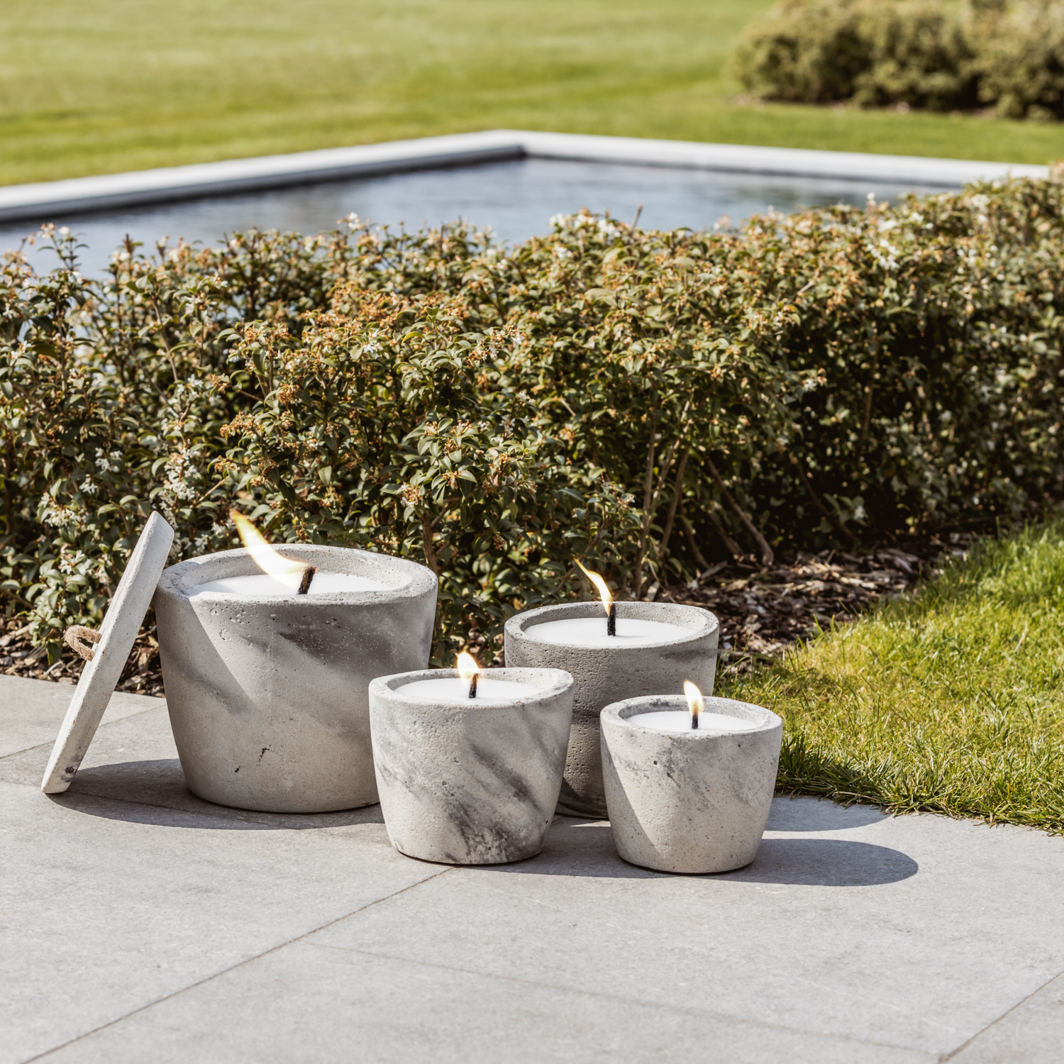 4 concrete candles of different sizes in a garden