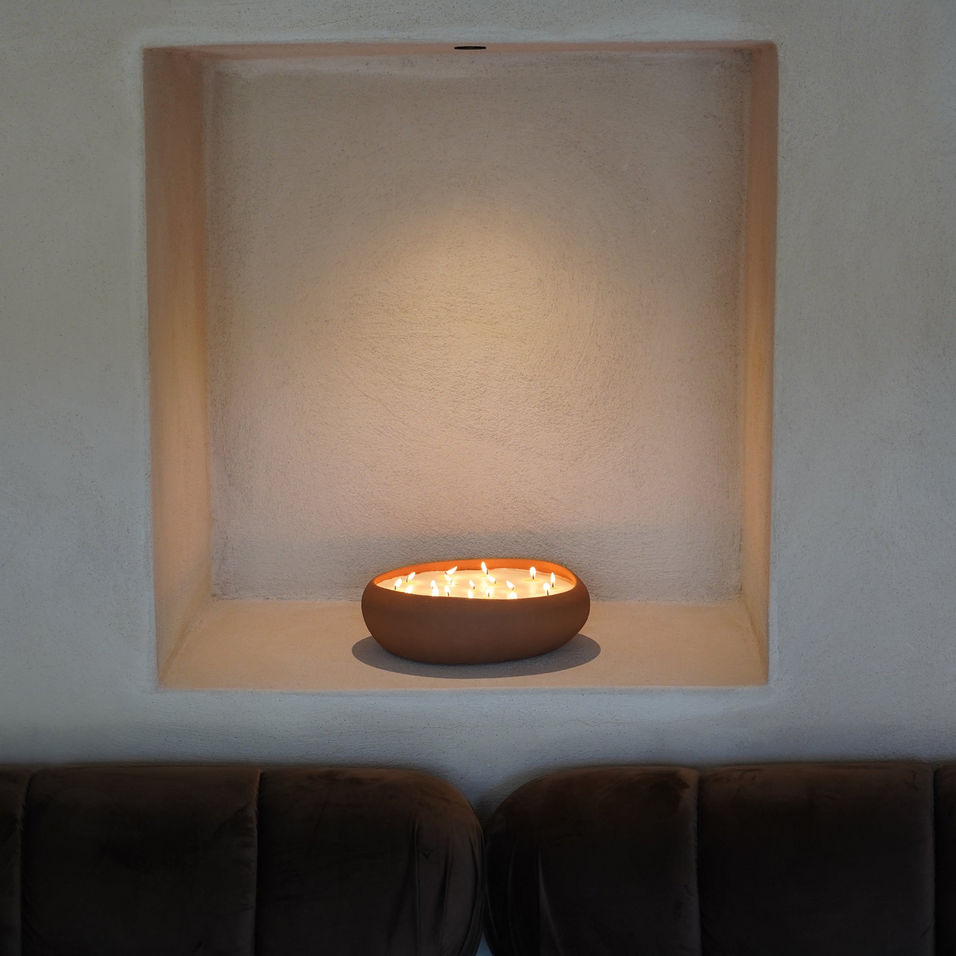 Candle in a decorative niche on a wall above a sofa