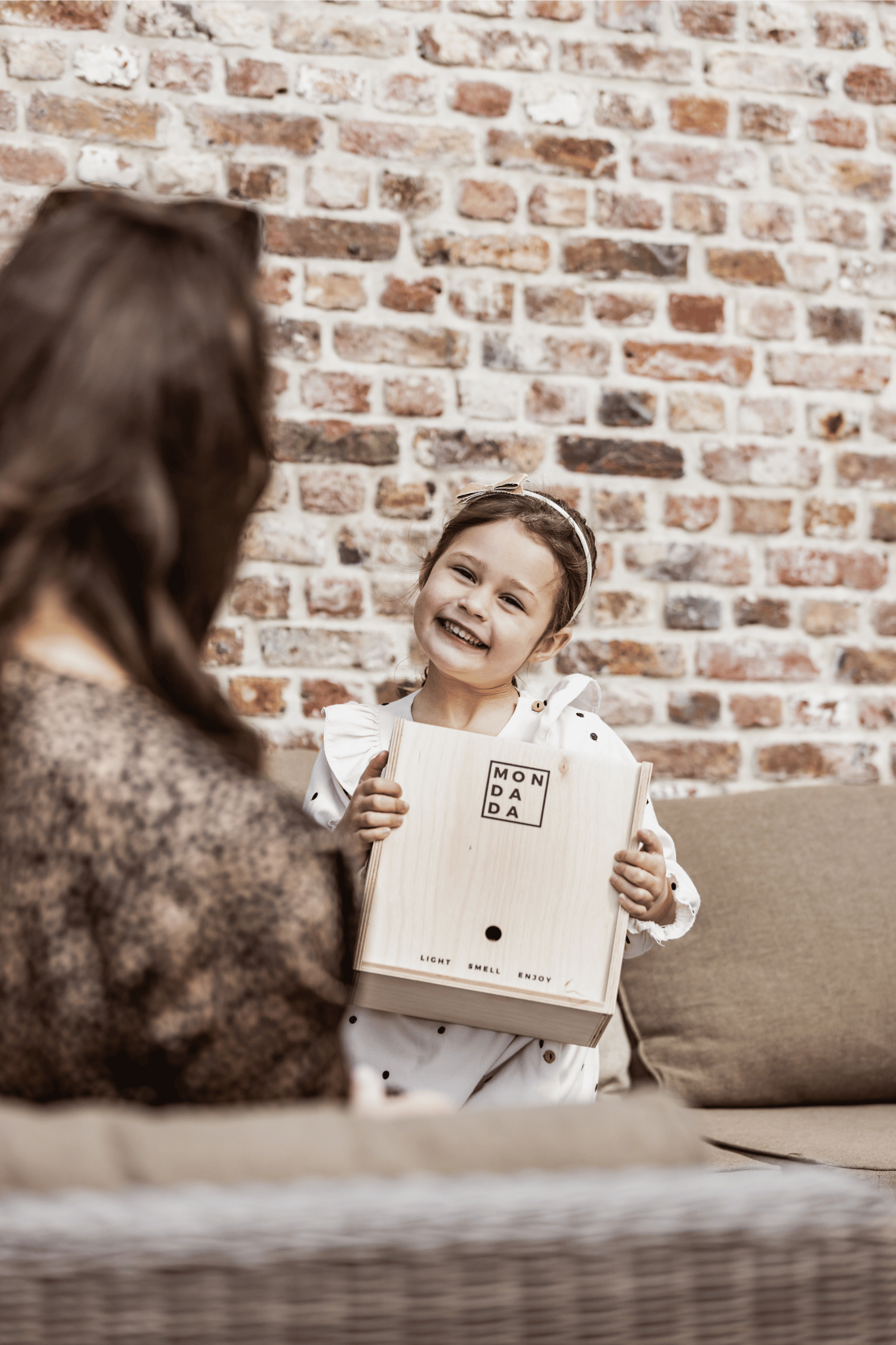 A little girl smiling and giving a gift to her mom